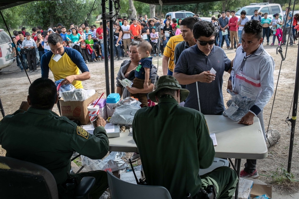 US Border Patrol agents interview immigrants, including a blind man from El Salvador, after taking them into custody in Los Ebanos, Texas, on Tuesday. — AFP