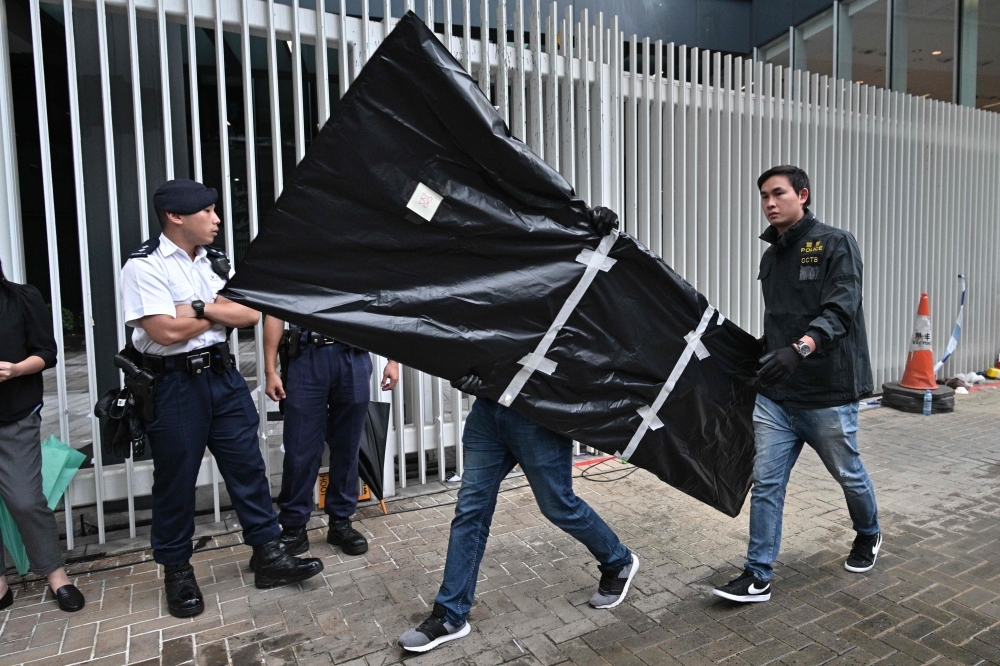 Police carry evidence out of the Legislative Council in Hong Kong on Wednesday, two days after protesters broke into the complex. — AFP