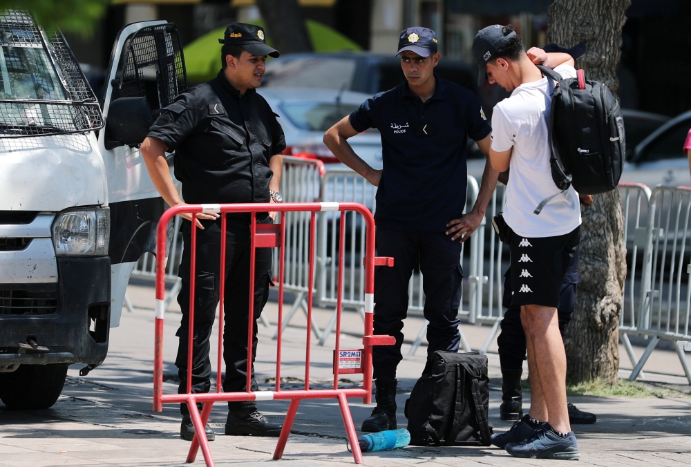 Police officers search the belongings of a civilian in Tunis, Tunisia, on Wednesday. — Reuters