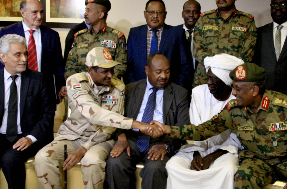 African union envoy to Sudan Mohamed al-Hacen Lebatt (L) sits next to Sudan's deputy chief of the ruling military council General Mohamed Hamdan Dagalo as he shakes hands with an army general following a press conference in Khartoum. AFP 