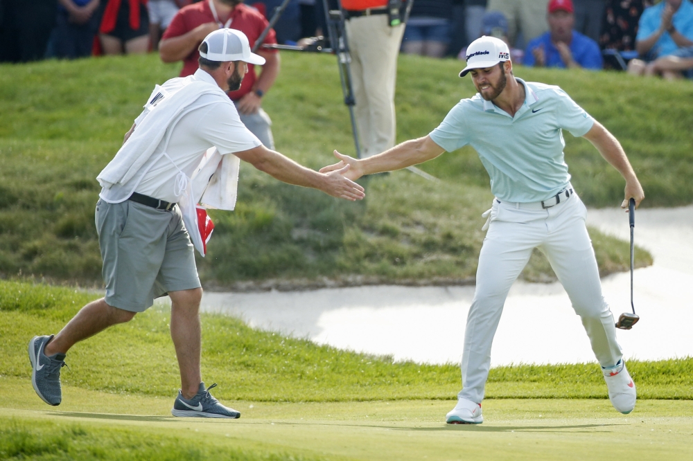 Matthew Wolff slaps the hand of his caddie Steve Lohmeyer (L) after sinking an eagle putt at the 18th hole to win 3M Championship golf tournament at TPC Twin Cities, Blaine, MN, USA, on Sunday. — Reuters