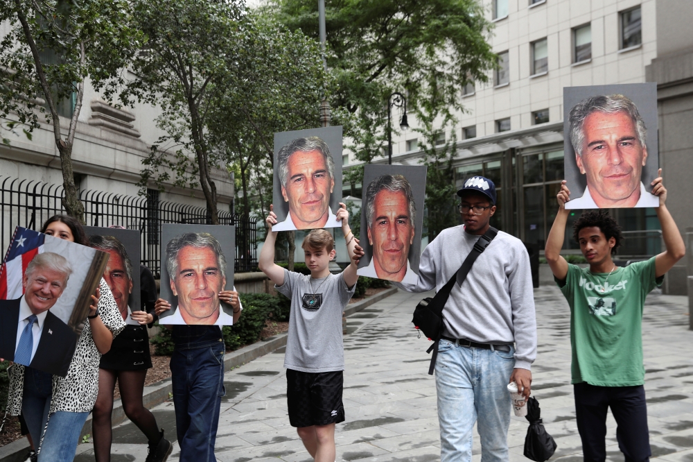 Demonstrators hold signs aloft protesting Jeffrey Epstein, as he awaits arraignment in the Southern District of New York on charges of sex trafficking of minors and conspiracy to commit sex trafficking of minors, in New York, on Monday. — Reuters