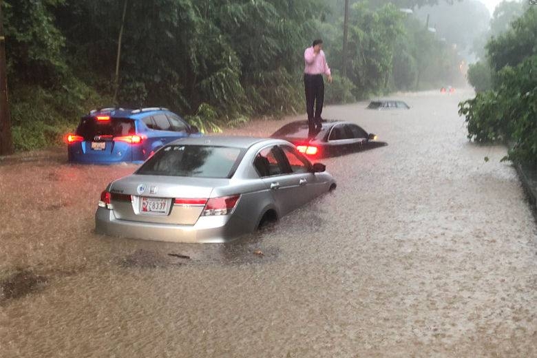 A driver stands on top of his car as roads flood in Washington on Monday. –Courtesy photo