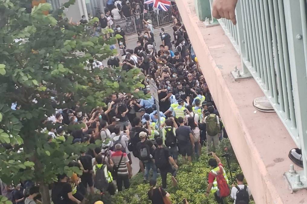 Police face off against protesters under a footbridge by Sheung Shui MTR station on Saturday. -Courtesy photo