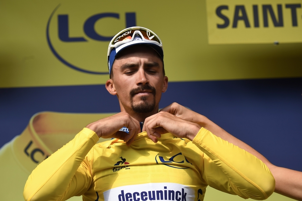 France's Julian Alaphilippe is helped to adjust his overall leader's yellow jersey on the podium of the eighth stage of the 106th edition of the Tour de France cycling race between Macon and Saint-Etienne, in Saint-Etienne, eastern France, on Saturday. — AFP