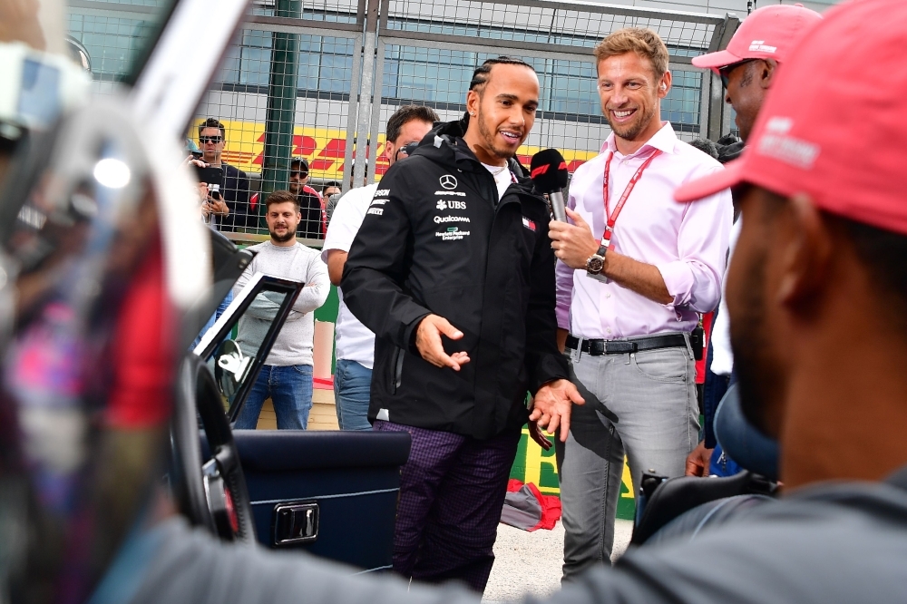 Mercedes' British driver Lewis Hamilton (C) chats with former driver Jenson Button before getting into a vintage MGC Roadster 1968, to be driven by his father Anthony on a parade lap ahead of the British Formula One Grand Prix at the Silverstone motor racing circuit in Silverstone, central England, on Sunday. — AFP