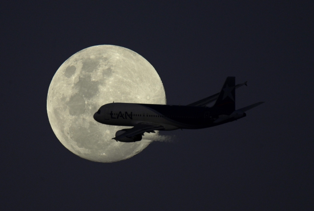 An airplane of LATAM Airlines flies in front of the moon after taking-off from Jorge Newbery airport in Buenos Aires, Argentina, on Monday. — AFP