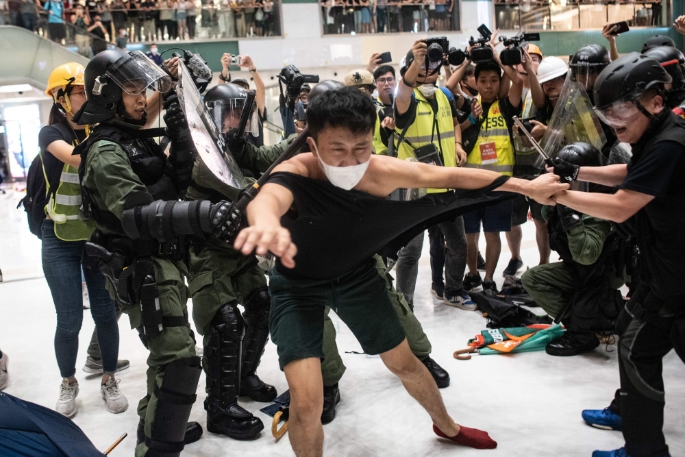  Police officers tear the shirt of a protester during a clash inside a shopping arcade after a rally against a controversial extradition law proposal in Sha Tin district of Hong Kong on July 14. -AFP photo