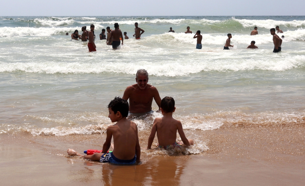 Youssef Kamoun, a 52-year-old nurse, sits near the water with his two children, Andrew, 7, and Adam, 5 at Ramlet Al-Bayda public beach in Beirut, Lebanon, in this July 7, 2019 file photo. — Reuters