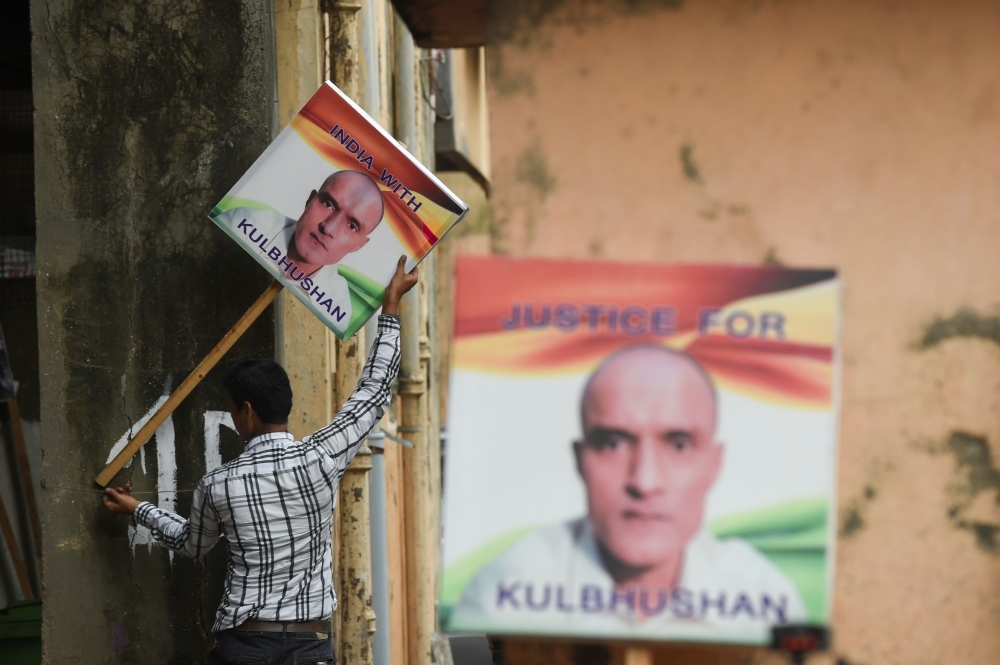 An Indian man holds a placard depicting Kulbhushan Jadhav, an Indian national convicted of spying in Pakistan, in the neighborhood where he grew up, in Mumbai, on Wednesday. — AFP