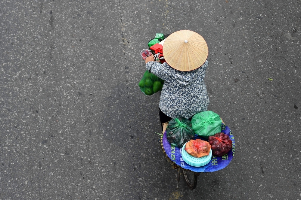 A fruit vendor cycles in Hanoi, Vietnam, on Thursday. — AFP