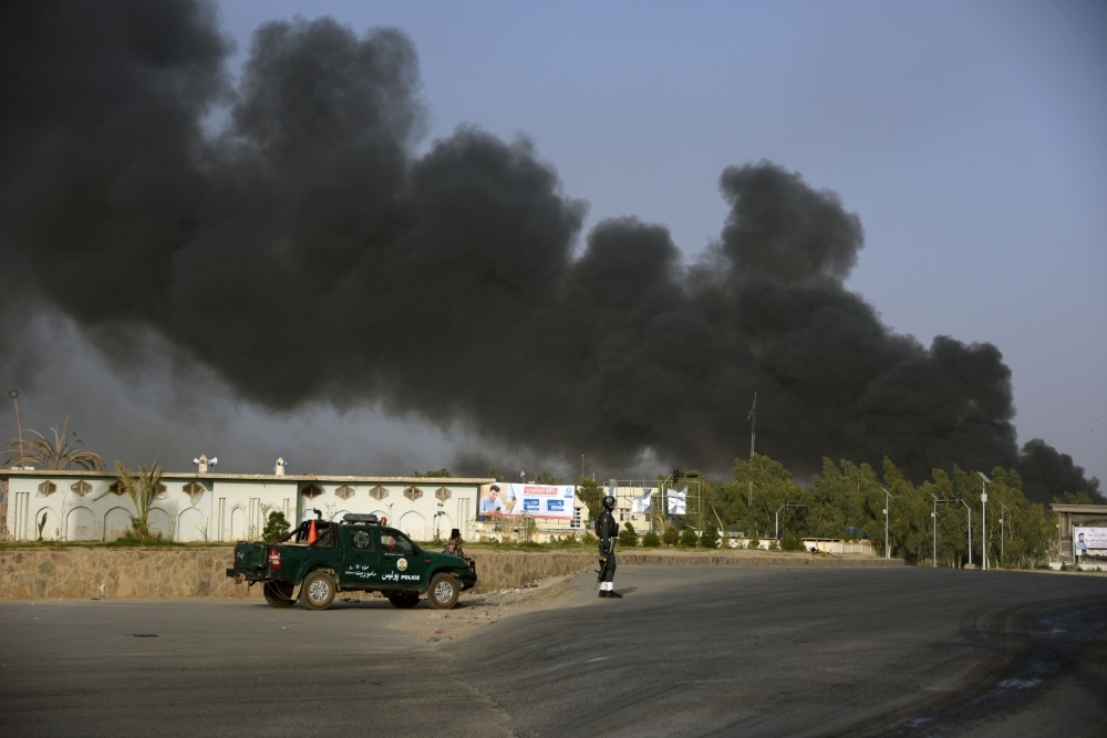 Afghan policemen arrive near a site of car bomb attack as smoke rises from the police headquarters in Kandahar province on Thursday. — AFP