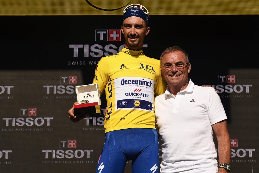 France's Julian Alaphilippe (L) poses with former French champion Bernard Hinault as he celebrates his overall leader's yellow jersey on the podium of the thirteenth stage of the 106th edition of the Tour de France cycling race, a 27,2-kilometer individual time-trial in Pau, on Friday. — AFP