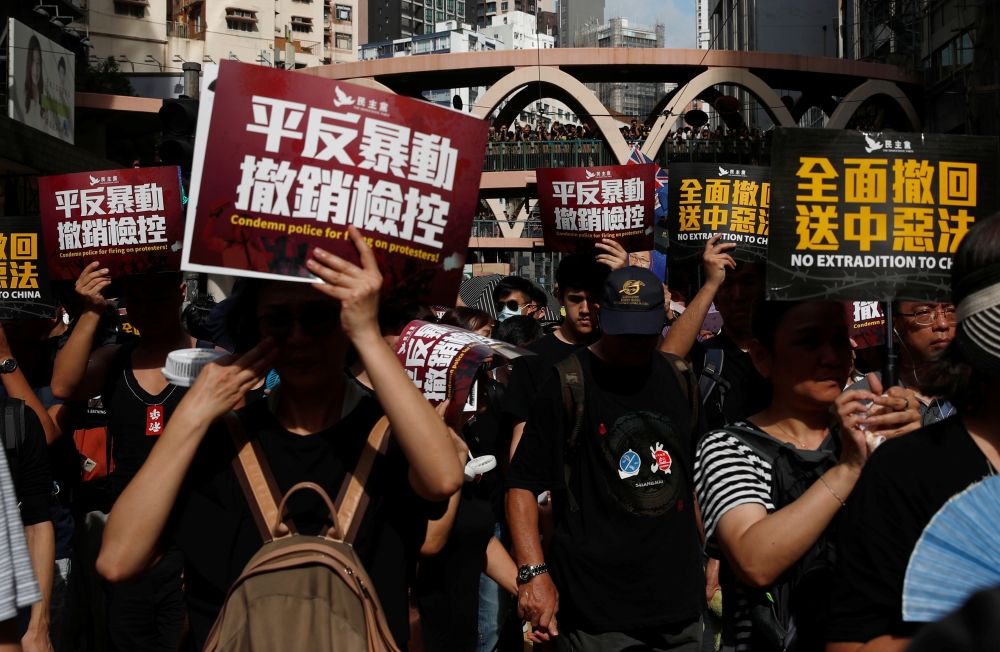 Anti-extradition demonstrators hold banners as they march to call for democratic reforms, in Hong Kong on Sunday. -Reuters