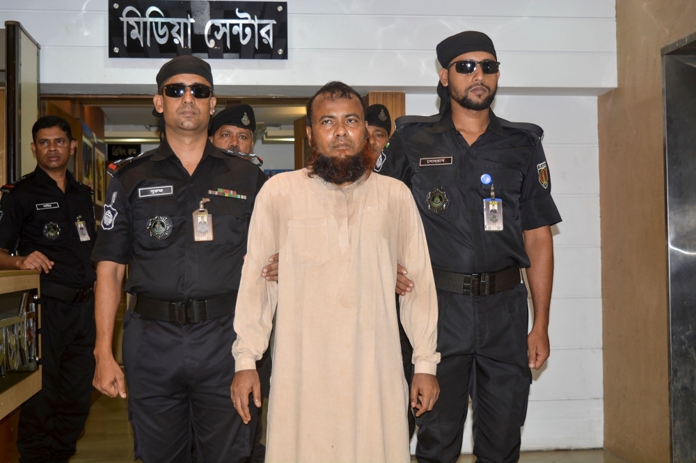 In this handout photo taken and released by the Bangladesh elite police Rapid Action Battalion (RAB) on Monday, officers escort Idris Ahmed, center, a cleric arrested for allegedly raping a dozen boys, in Dhaka on Monday. — AFP