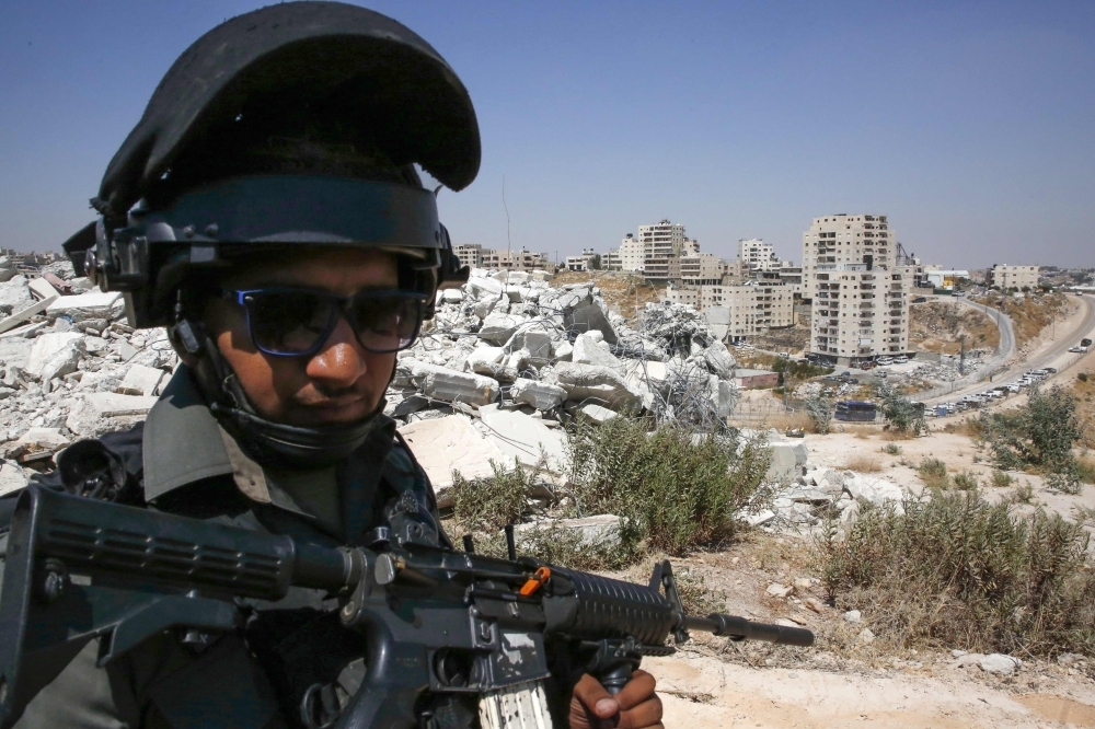 A member of the Israeli border police stands guard in front of buildings demolished by Israel in the West Bank village of Dar Salah in the area of Sur Bahir east Jerusalem, on JMonday. — AFP