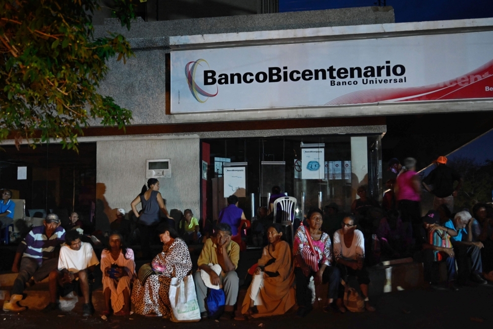 People get ready to spend the night outside a bank in Maracaibo, Zulia State, Venezuela on Monday to collect their pensions the next day, as parts of the country, including the capital Caracas, were hit by a massive power cut. -AFP