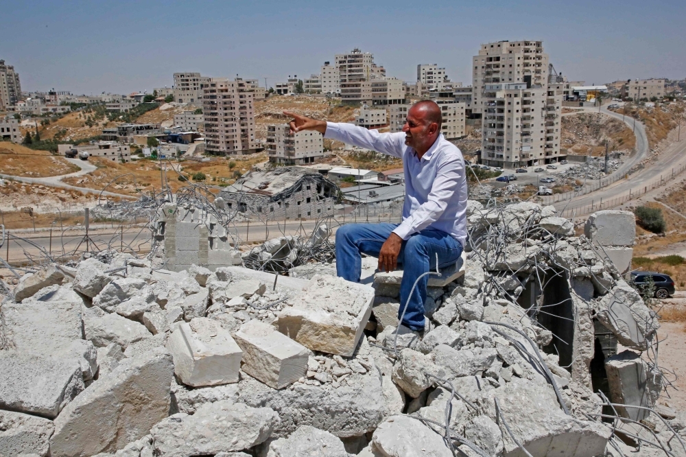 A picture taken in Dar Salah on Wednesday shows Akram Zwahreh sitting on top of the rubble of his house during a tour for Fatah Movement to the site of demolished buildings in the West Bank, adjacent to the area of Sur Baher in East Jerusalem. — AFP