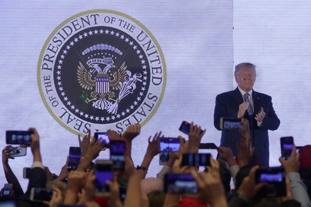 US President Donald Trump applauds in front of a doctored presidential seal with a double headed eagle and a set of golf clubs as he arrives to address the Teen Student Action Summit on Tuesday in Washington, DC. Conservative high school students gathered for the 4-day invited-only conference hosted by Turning Point USA to hear from conservative leaders and activists, receive activism and leadership training, and network with other attendees and organizations from across the US. — AFP