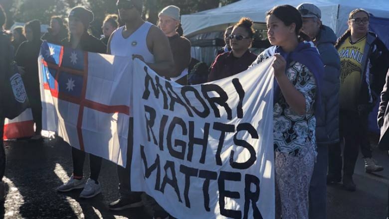 Protesters at Ihumātao holding a banner reading 