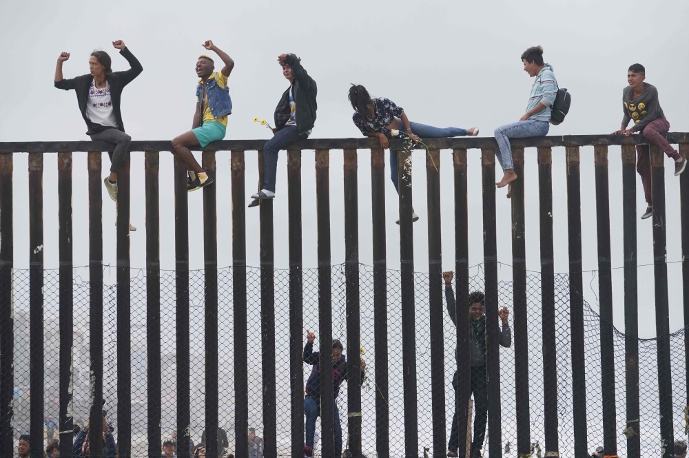 In this file photo taken on April 29, 2018, migrant caravan demonstrators climb the US-Mexico border fence during a rally in San Ysidro, California. -AFP photo