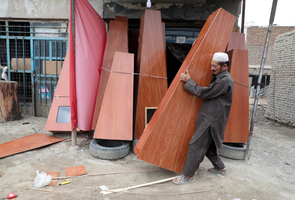 An Afghan carpenter prepares coffins for sale at his shop in Kabul, Afghanistan, on Monday. — Reuters