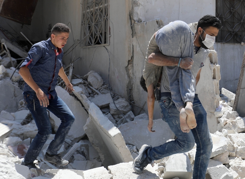 A Smember of the Syrian Civil Defense (White Helmets) inspects a victim at the site of a reported air strike on the town of Ariha, in the south of Syria's Idlib province, in this July 27, 2019 file photo.  — AFP