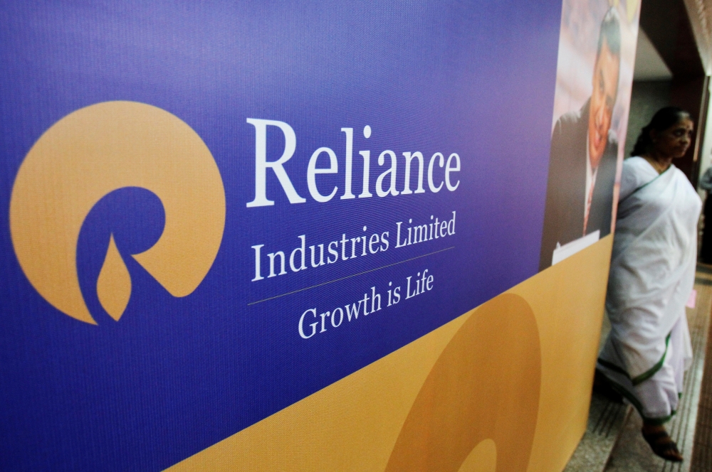 A woman walks past a poster of Reliance Industries installed outside the venue of the company's annual general meeting in Mumbai in this June 7, 2012 file photo. — Reuters