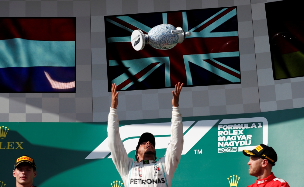 Mercedes' Lewis Hamilton celebrates winning the Hungarian Grand Prix on the podium with his trophy while Red Bull's Max Verstappen and Ferrari's Sebastian Vettel look on in Budapest, Hungary, on Sunday. — Reuters