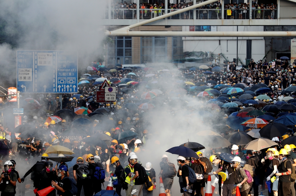 Protesters react after tear gas was fired by the police during a demonstration in support of the city-wide strike and to call for democratic reforms outside Central Government Complex in Hong Kong, on Monday. -Reuters
