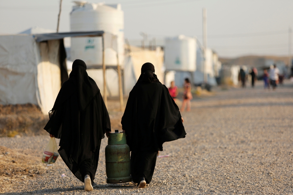 Displaced Iraqi women, who return to camp after trying to go home and find the conditions in their towns unbearable, with lack of services and destroyed buildings,carry a jar of gas at Hassan Sham camp, east of Mosul, Iraq, in this July 29, 2019 file photo. — Reuters