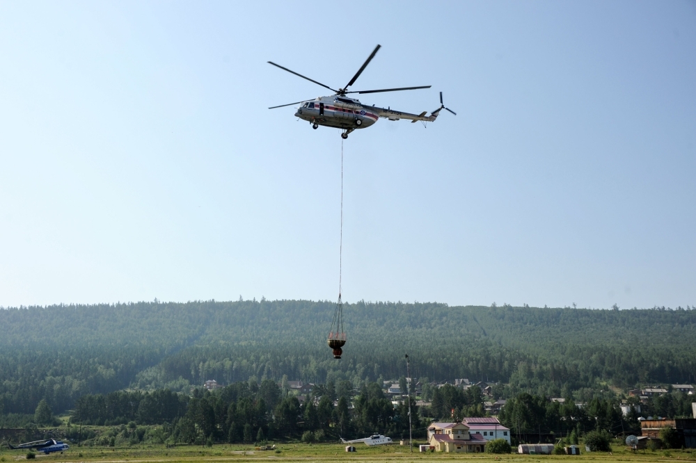 A Russian Emergency Ministry helicopter with a water tank flies over an airfield in the settlement of Boguchany in Russia's Krasnoyarsk Krai in this Aug. 3, 2019 file photo. — AFP