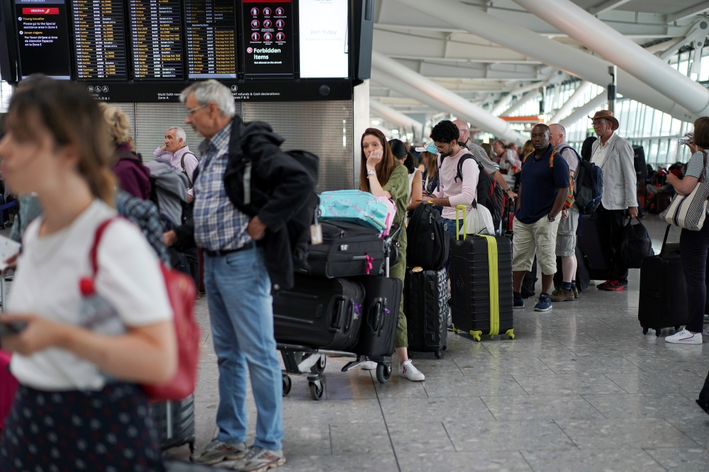 People queue inside Terminal 5 at Heathrow Airport as IT problems caused delays in London on Wednesday. — Reuters