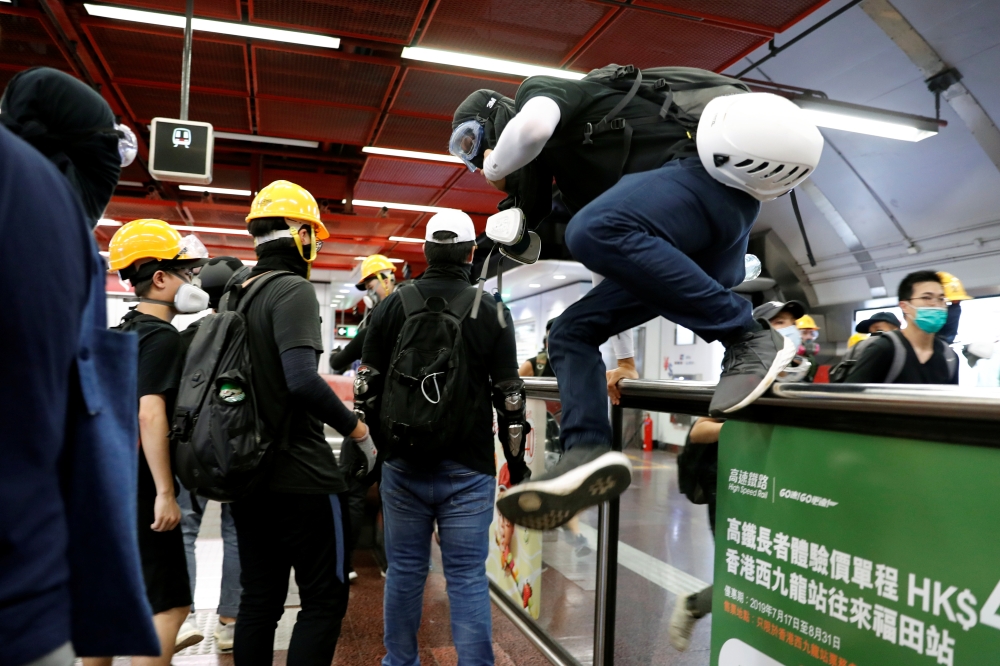 Anti-Extradition bill protesters run inside Taikoo Shing Mass Transit Railway (MTR) station, after police detained protesters inside a station in Hong Kong, on Sunday. -Reuters