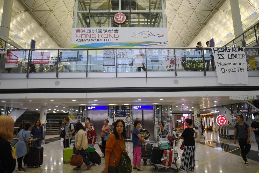 Passengers arrive at Hong Kong's international airport as pro-democracy protesters gather during a demonstration against police brutality and the controversial extradition bill at Hong Kong's international airport on Monday. — AFP