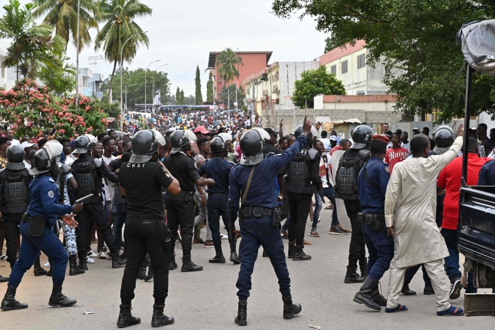 Riot police officers try to disperse people gathered outside an hospital in Abidjan on Monday, after Ivorian singer DJ Arafat, star of the 