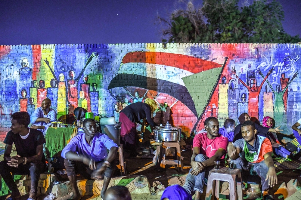 In this file photo taken on April 24, 2019, Sudanese protesters sit in front of a recently painted mural during a demonstration near the army headquarters in the capital Khartoum. -AFP