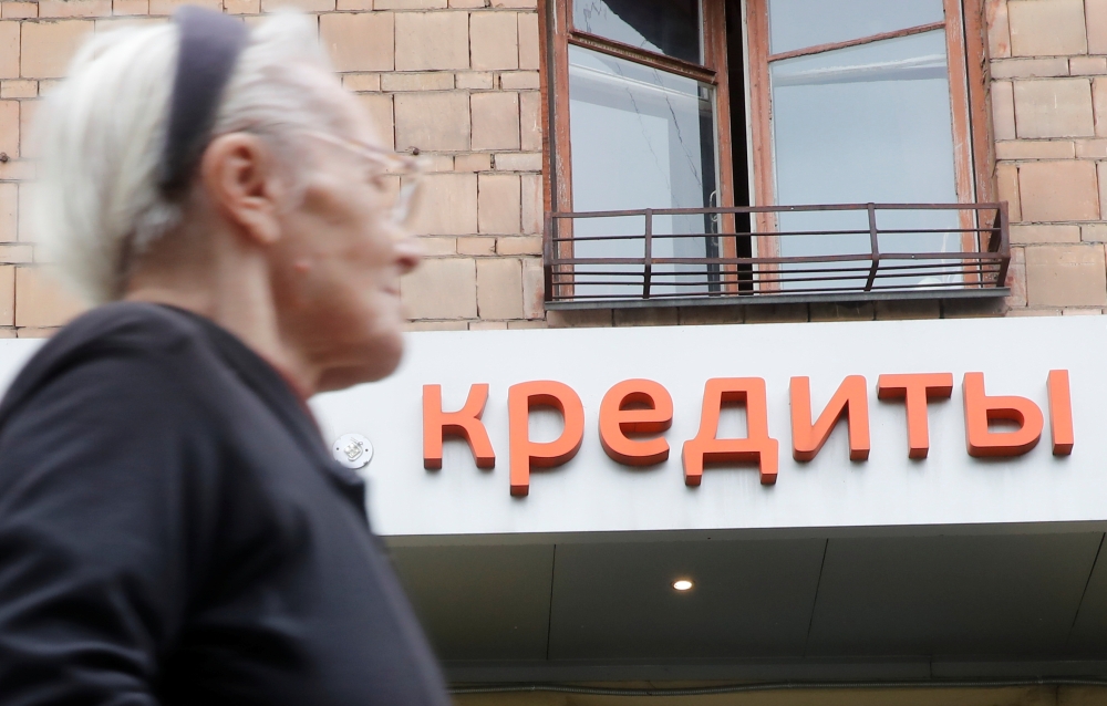 A woman walks past an office of a local bank in Moscow, Russia on Wednesday. The signboard reads 