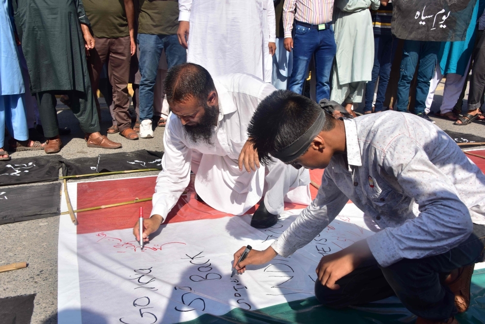 Activists of Hizbul Mujahideen (HM), a Kashmiri separatist group, write comments on an Indian flag during a protest in Muzaffarabad, the capital of Pakistan-controlled Kashmir on Thursday, as the country observes 'Black Day' on India's Independence Day over the recent move to strip Indian-administered Kashmir of its autonomy. — AFP