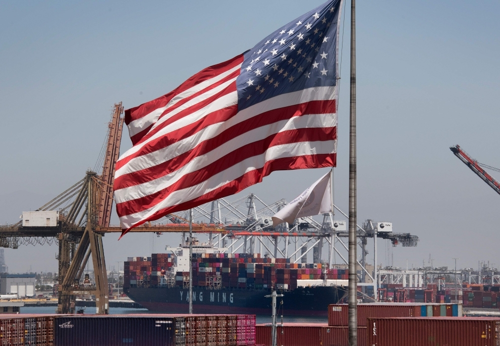 In this file photo taken on August 1, 2019 The US flag flies over a container ship unloading it's cargo from Asia, at the Port of Long Beach, California. -AFP