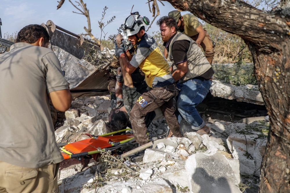Syrians and members of Syrian Civil Defense recover a body from the rubble after a reported air strike by regime planes on the town of Maaret Hurmah in the southern countryside of Syria's northwestern Idlib province, in this Aug. 14, 2019 file photo. — AFP