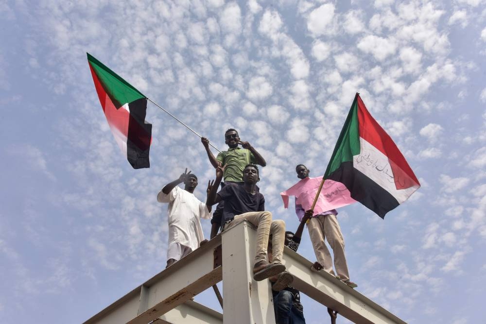 Sudan's protest leader Ahmad Rabie (2nd-right) flashes the victory sign alongside Gen. Abdel Fattah Al-Burhan (center), the chief of Sudan's ruling Transitional Military Council (TMC), during a ceremony where they signed a 