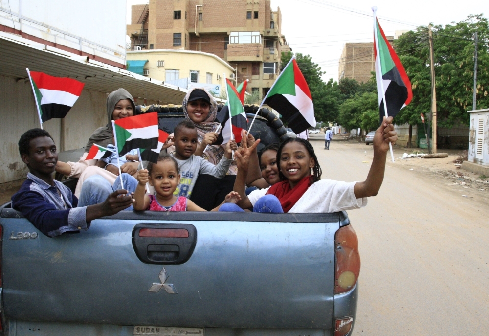 Sudanese children wave small national flags as people celebrate outside the Friendship Hall in the capital Khartoum where generals and protest leaders on Saturday signed a historic transitional constitution meant to pave the way for civilian rule in Sudan. — AFP