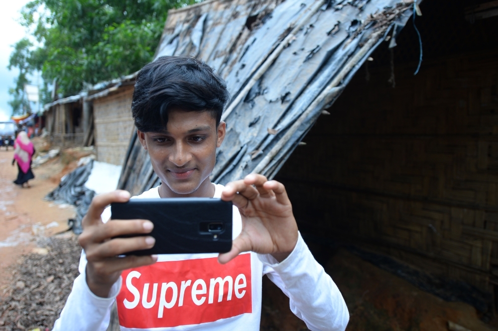In this picture taken on July 23, 2019, Rohingya youth Mohammad Rafiq uses his mobile phone to take photos at the Kutupalong refugee camp. -AFP