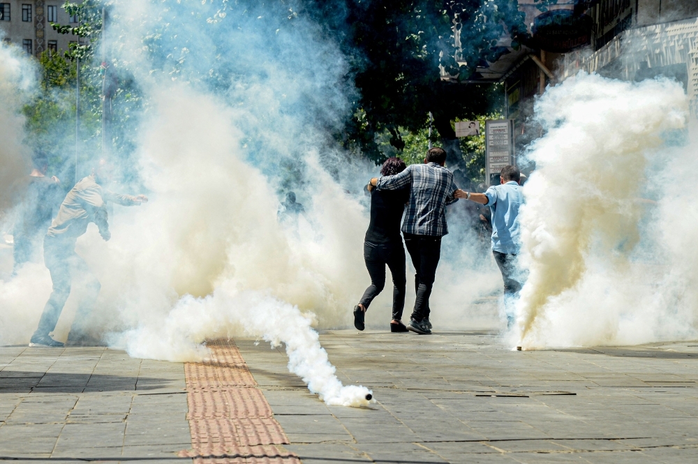 Turkish anti-riot police officers use their shields to disperse demonstrators during a protest against the replacement of Kurdish mayors with state officials in three cities, in Diyarbakir, Turkey, on Tuesday. — AFP