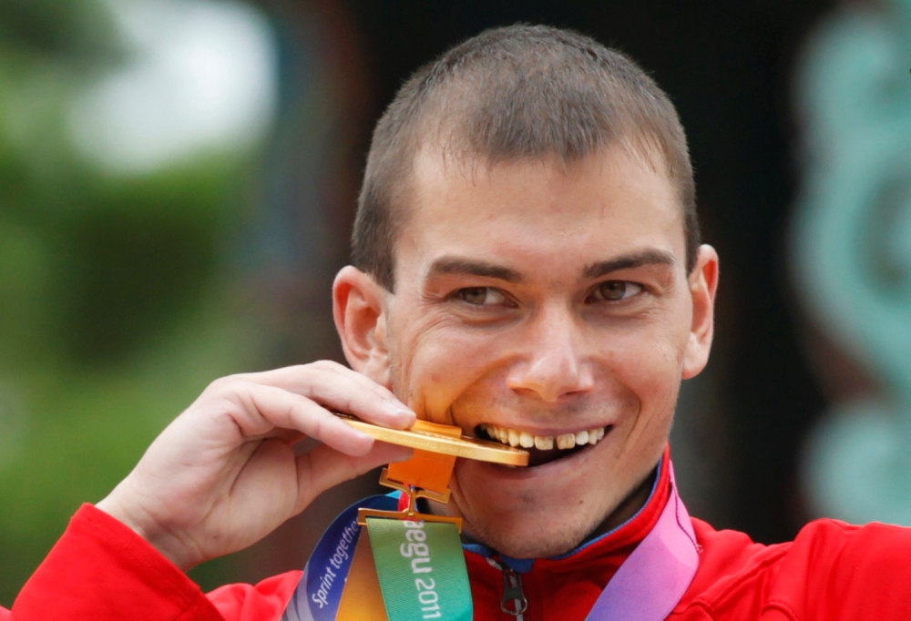 Sergey Bakulin of Russia bites his gold medal after the men's 50 km race walk final at the IAAF World Athletics Championships in Daegu, in this Sept. 3, 2011 file photo. — Reuters