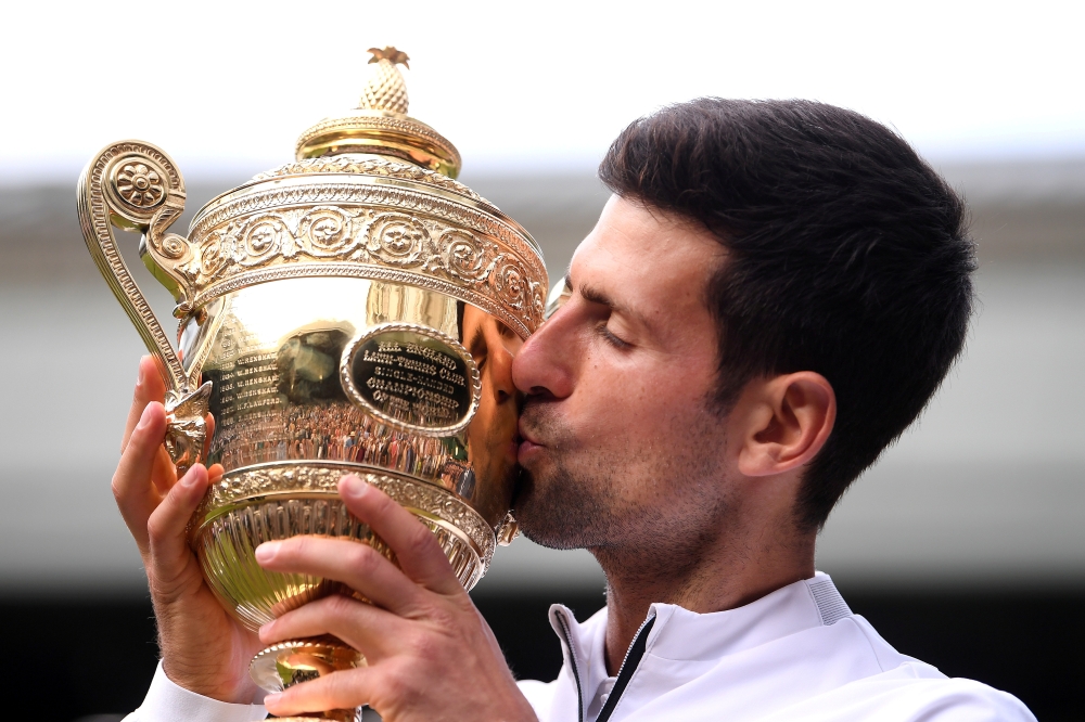 Serbia's Novak Djokovic kisses the trophy as he poses for photographs after winning the final against Switzerland's Roger Federer at Wimbledon, London, in this July 14, 2019 file photo. — Reuters
