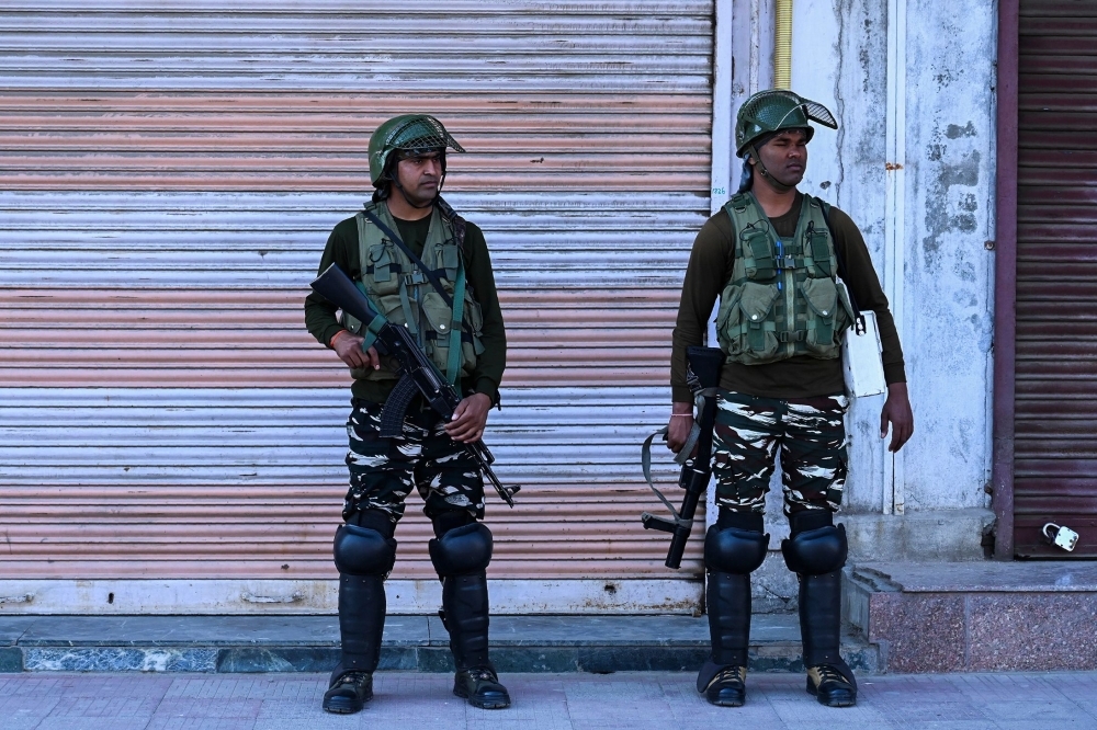 Security personnel stand guard on a street near closed shops in Srinagar, India, on Thursday. — AFP