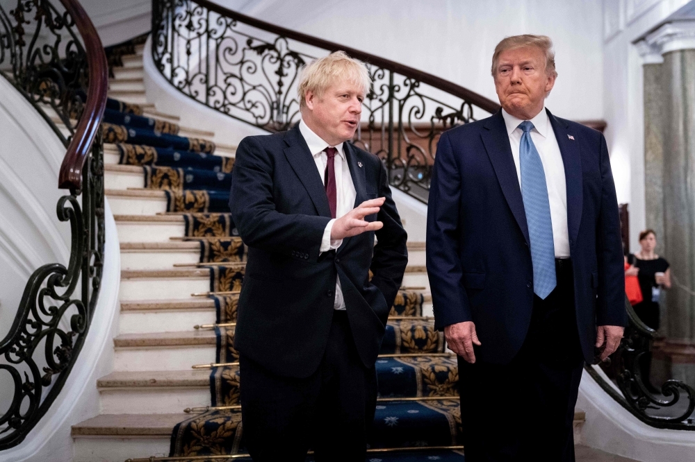 US President Donald Trump (R) and Britain's Prime Minister Boris Johnson speak before a working breakfast at the G7 Summit in Biarritz, France on Sunday. -AFP