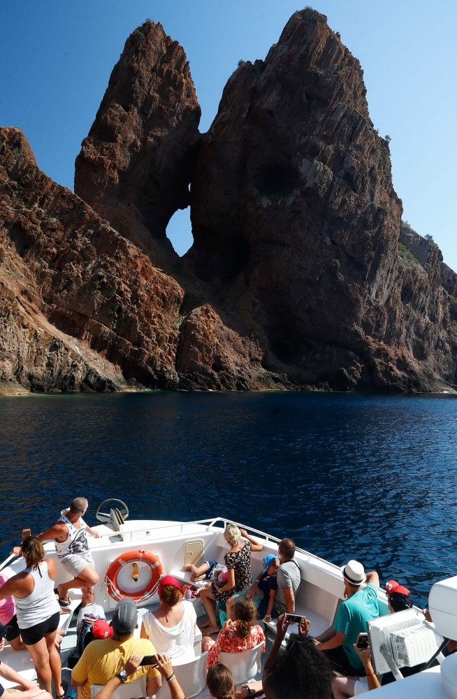 Tourists take a cruise on August 19, 2019, in the Scandola Nature Reserve, on the western coast of the French Mediterranean island of Corsica. -AFP